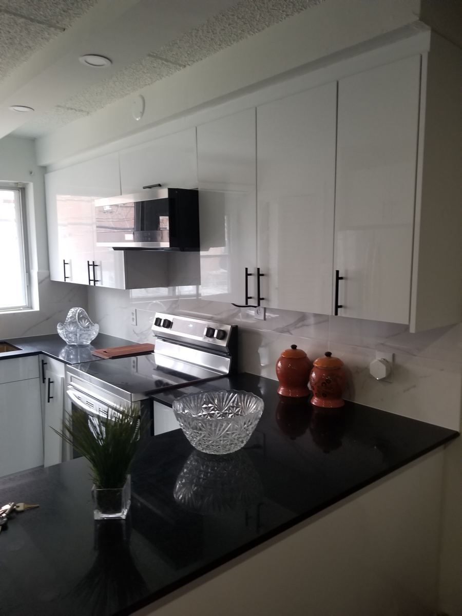 Cuisine blanche lustrée avec comptoir noir installée par Ébénisterie Générale